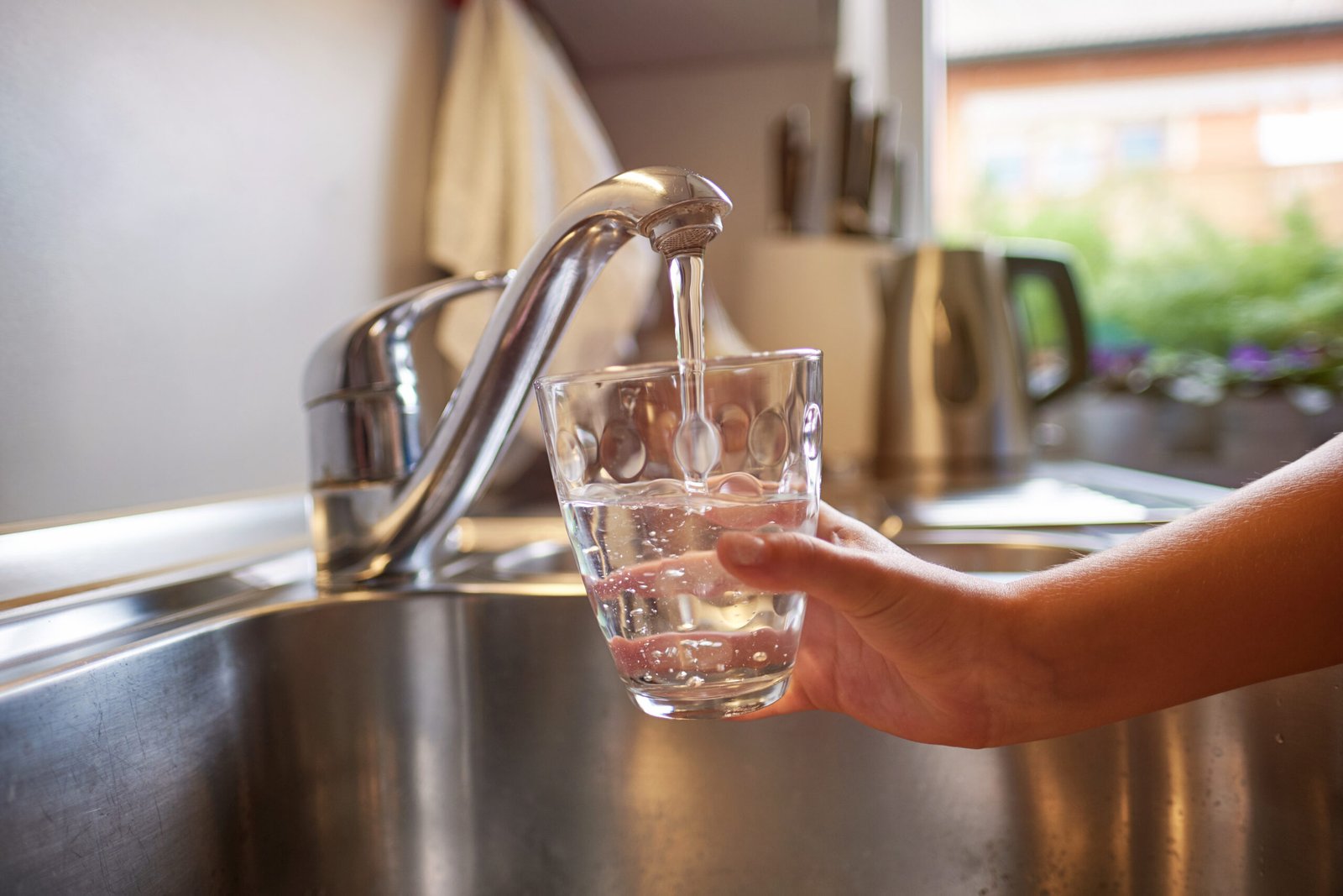 close up of children hands, pouring glass of fresh water from ta